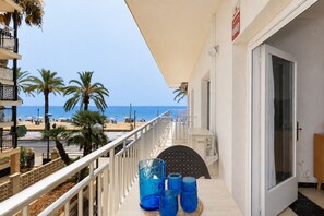 A balcony with a view of the beach, palm trees, and the sea.