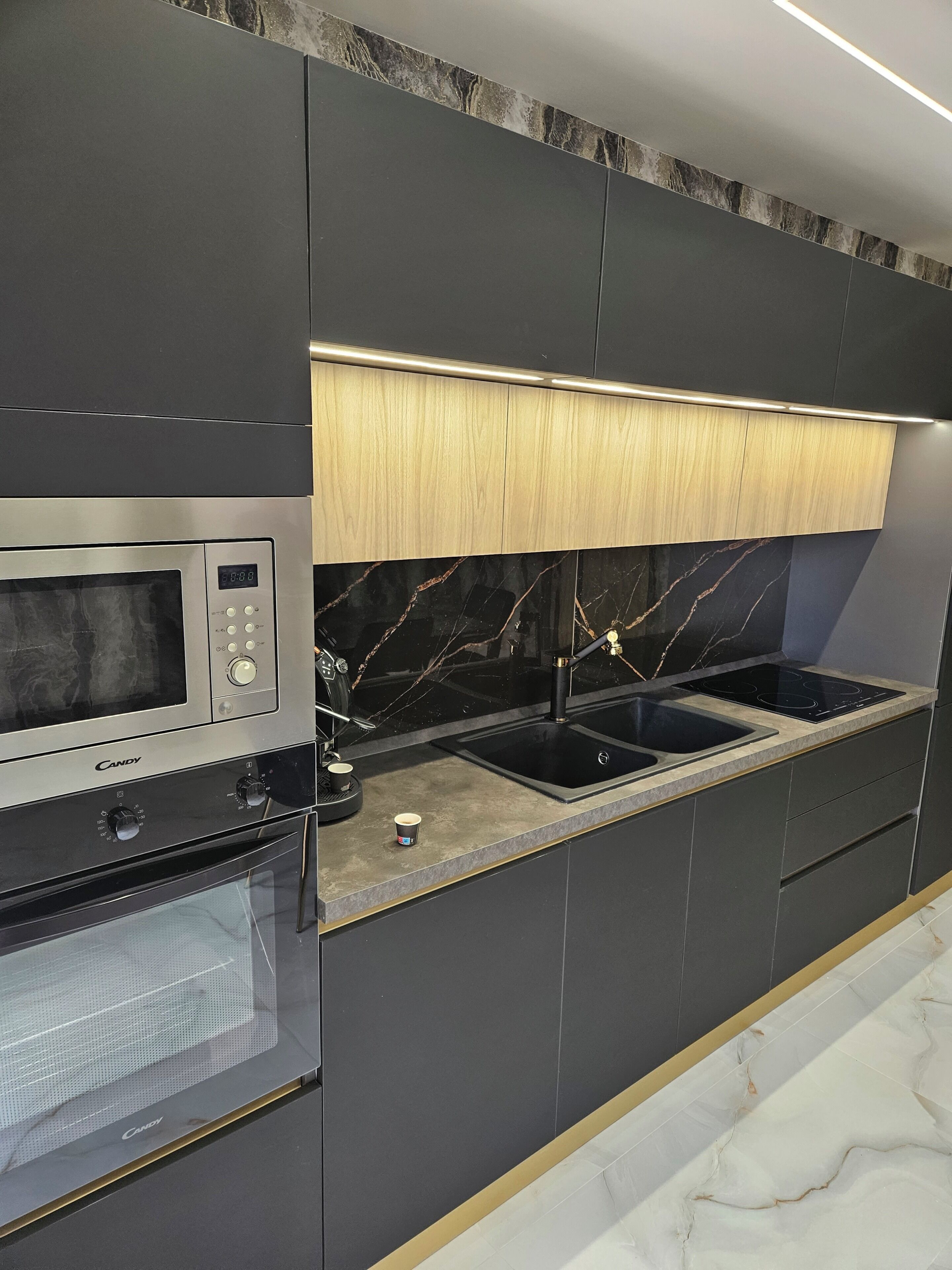 Una cucina moderna con forno a microonde integrato, forno e lavello a due vasche.