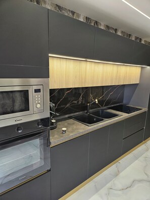 A modern kitchen with a built-in microwave, oven, and a double sink. - A self-contained apartment equipped with all the amenities, located near the subway and all forms of public transportation (Napoli)