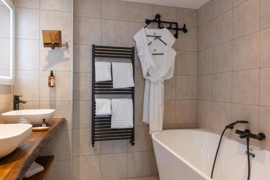 Une salle de bain moderne avec une baignoire sur pieds, un porte-serviettes avec deux serviettes et un meuble-lavabo en bois avec un évier.