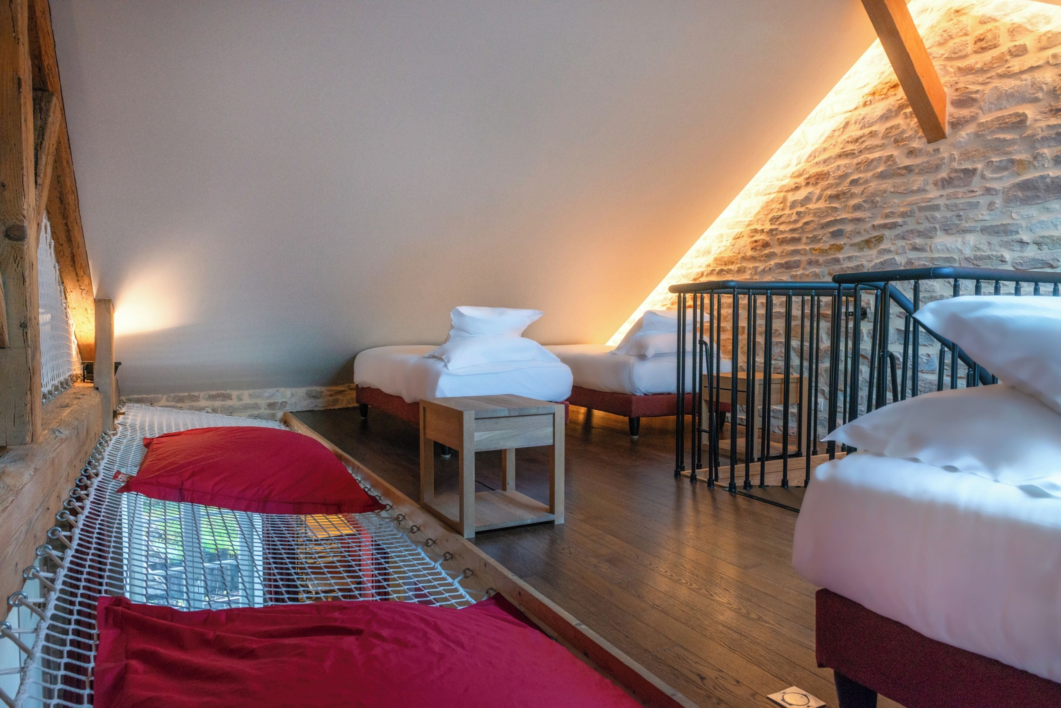 A cozy, sloped-roofed room with a bed, two chairs, and a small table.