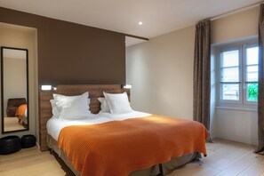 A bedroom with a bed, a mirror, a window with curtains, and a wooden headboard. - Hotel Aux Terrasses  (Tournus)