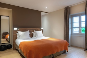 Un dormitorio con cama, espejo, ventana con cortinas y cabecera de madera.
