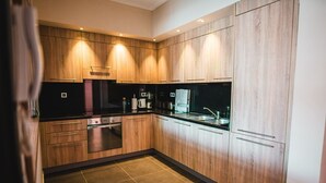 Eine moderne Küche mit Holzschränken, einer schwarzen Arbeitsplatte und Edelstahlgeräten.