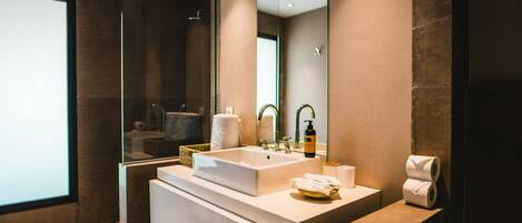 A modern bathroom with a large mirror, a white sink, and a glass shower enclosure.