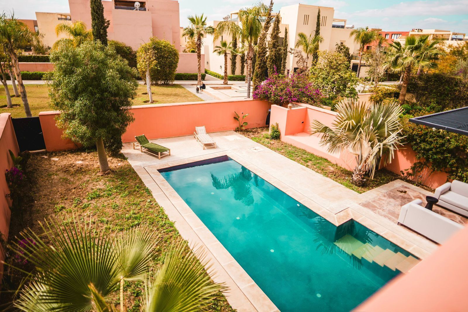 Una piscina con sillas de descanso y un pequeño jardín.