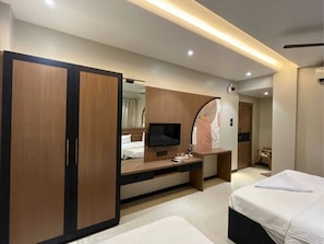 Een moderne hotelkamer met een bed, een bureau, een televisie en een kledingkast.