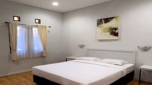 A bedroom with a large bed, a bedside table, a wall-mounted light, and a window with curtains. - Cozzy Villa Mandala Wangi Pangalengan (Pangalengan)