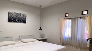 A bedroom with a large bed, a bedside table, a hanging light, and a window with curtains. - Cozzy Villa Mandala Wangi Pangalengan (Pangalengan)