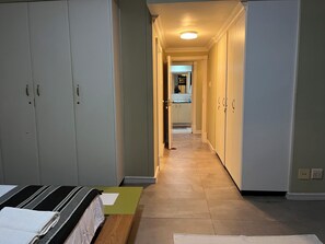 A hallway with a bed, a bench, and a bathroom visible in the distance.
