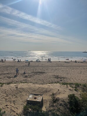 Una playa con gente, sombrillas y cielo despejado.