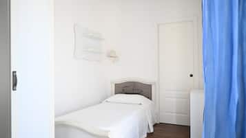 Ein Schlafzimmer mit einem Einzelbett, einer weißen Tür und einem blauen Vorhang.