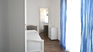 Un dormitorio con cama, un escritorio pequeño y ventana con cortinas.