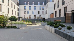 A modern building with multiple floors, a central courtyard with pathways, and various plants. - Klonova Apartment in Masuria (Olecko)