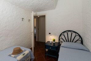 Ein Schlafzimmer mit einem Bett, einem Nachttisch, einer Lampe und einem Hut auf dem Bett.