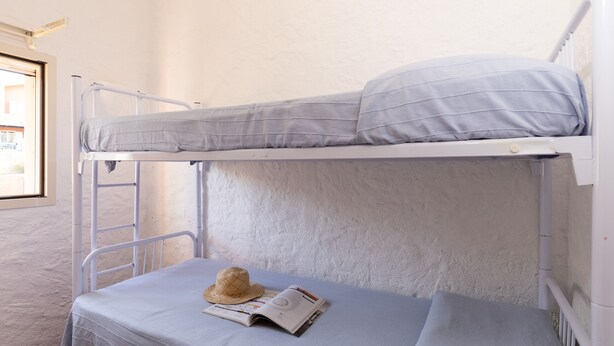 Un letto a castello con una scala, un cappello e una rivista sullo strallo inferiore.