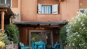 Un patio con mobili da esterno, una zona salotto coperta e un solarium a bordo piscina.