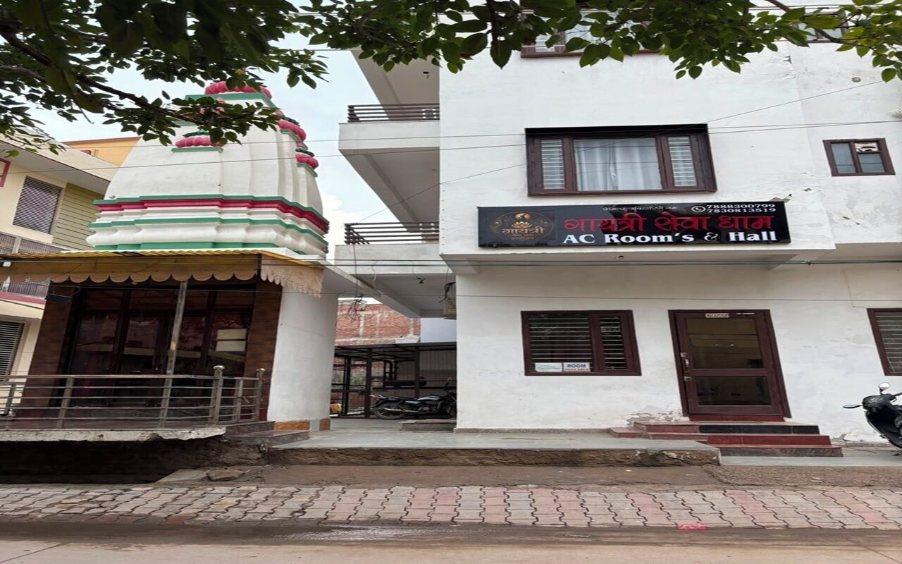 A building with a sign for 'AC Room's & Hall' and a small shrine-like structure with a red and green roof.