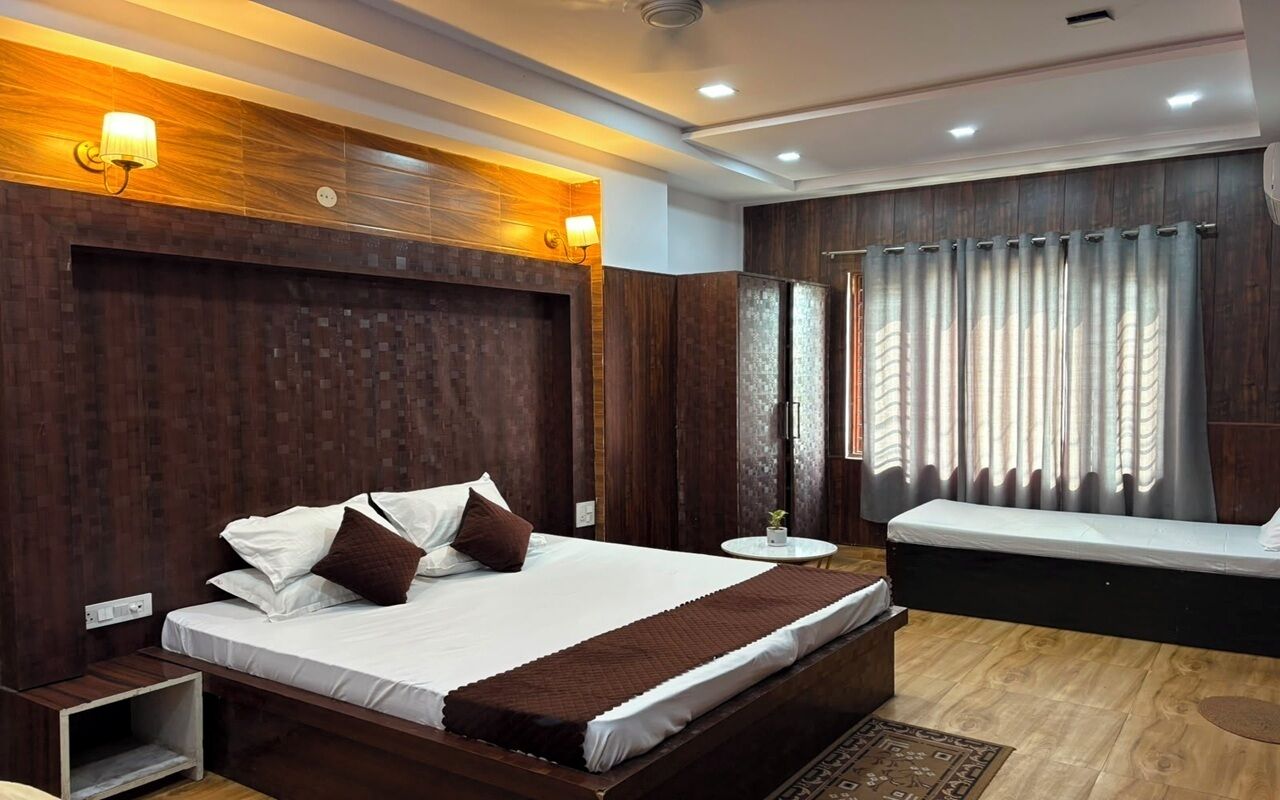 A modern bedroom with a large bed, bedside tables, a small round table, and a built-in bench.