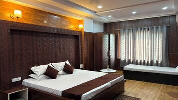 A modern bedroom with a large bed, bedside tables, a small round table, and a built-in bench.