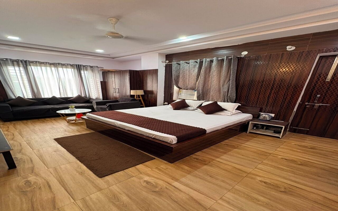 Una habitación de hotel moderna con una cama grande, un sofá, una mesita y un armario.