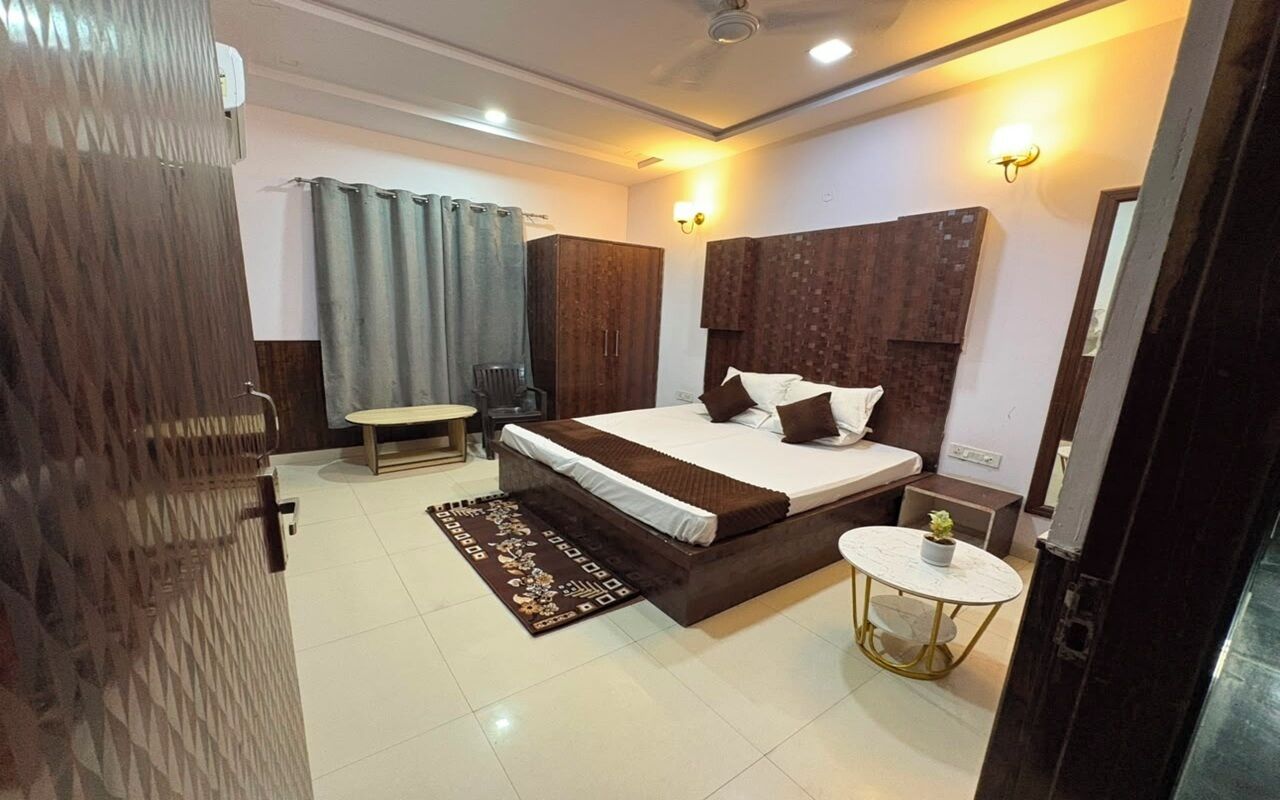 A hotel room with a bed, bedside table, chair, and a small round table with a plant.