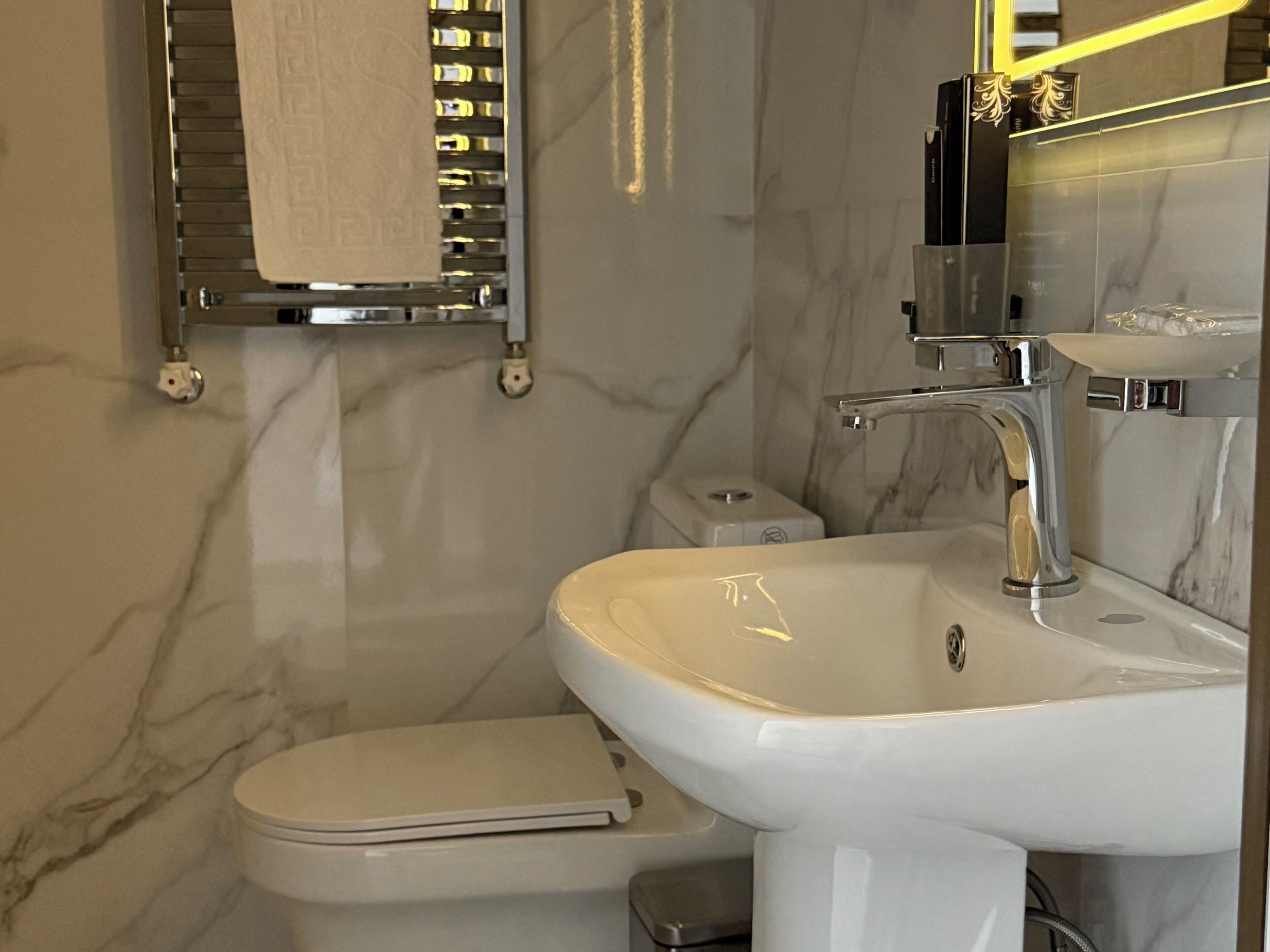 A modern bathroom with a white sink, a toilet, and a towel rack.