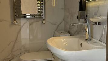 A modern bathroom with a white sink, a toilet, and a towel rack.