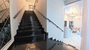 Una escalera moderna con barandilla de vidrio que conduce a una sala de estar con un sofá y una mesa de centro.