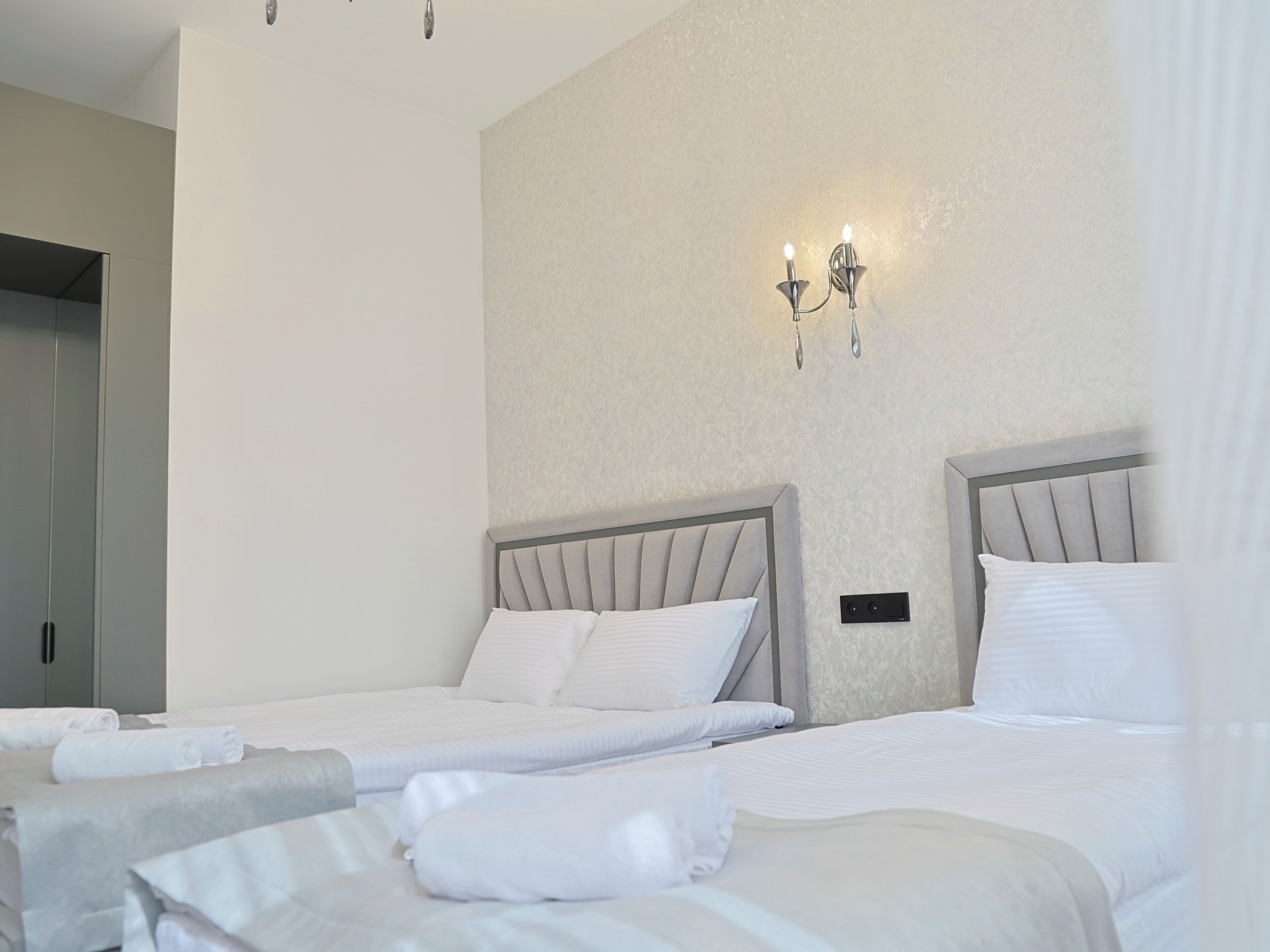 Ein Hotelzimmer mit zwei Betten, einer Wandleuchte und einer Tür.