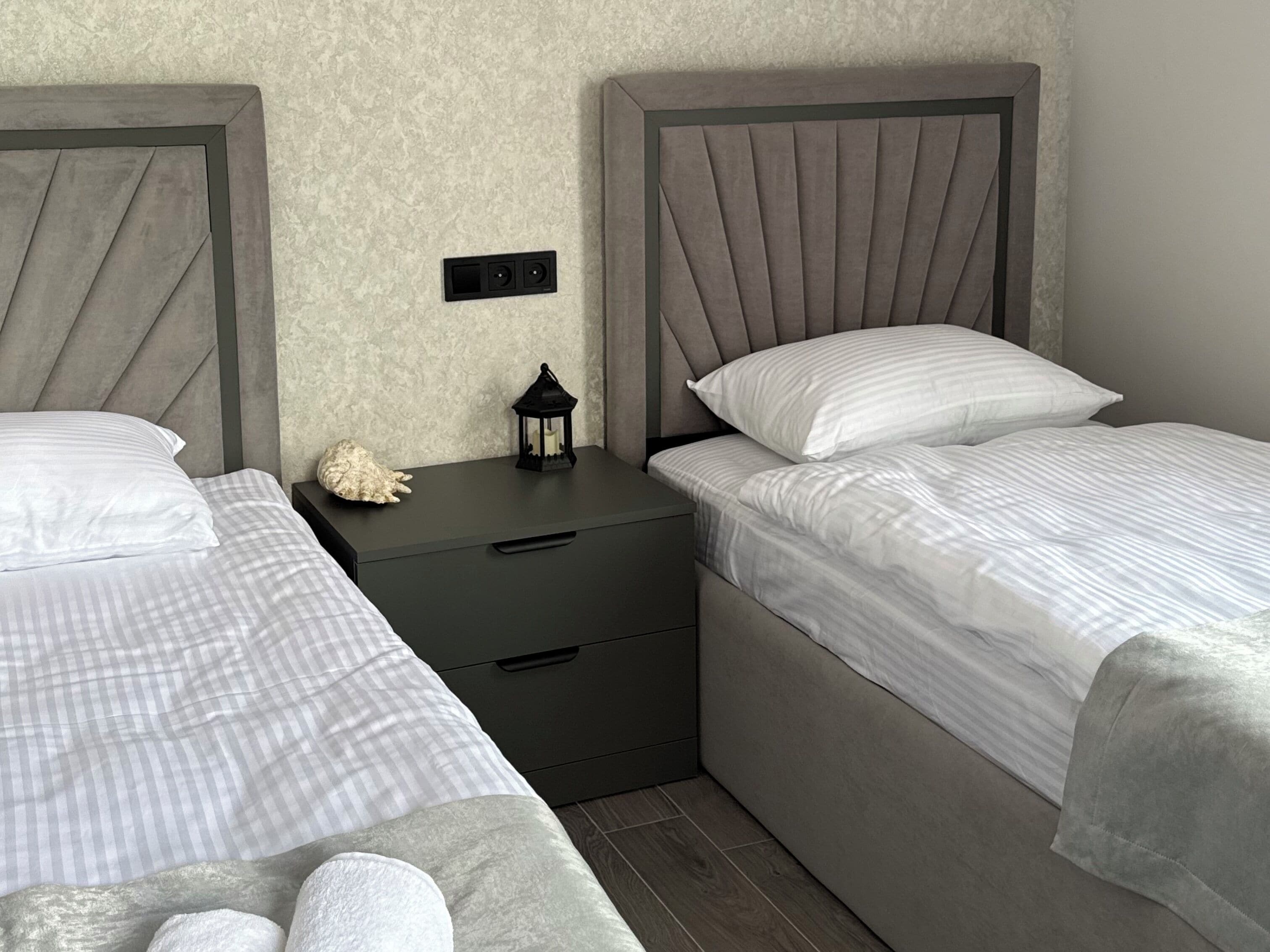 Een slaapkamer met twee eenpersoonsbedden, een nachtkastje, een lamp en een decoratief object.