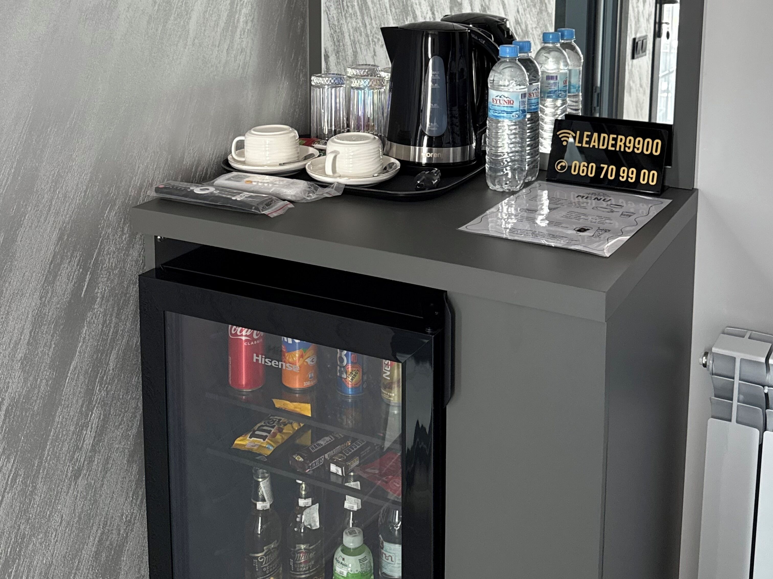 A minibar with a selection of beverages, a coffee maker, and a water dispenser.