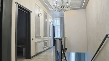 Ein Korridor mit Marmorboden, einem Chandelier und einer Treppe mit Metallgeländer.