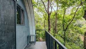 Un balcón con vistas a una vegetación densa y árboles.