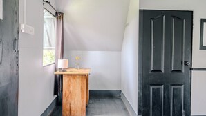 Un pasillo estrecho con un armario de madera, una mesita con una lámpara y una puerta oscura.