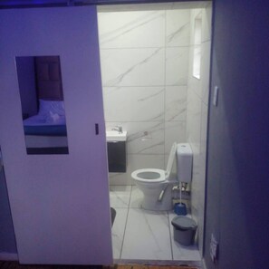 A small bathroom with a toilet, sink, and a trash bin.