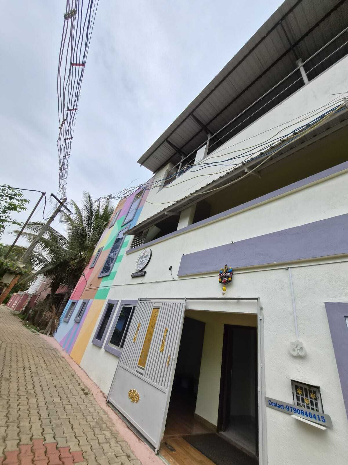A multi-story building with a colorful facade, a gated entrance, and a contact number displayed.