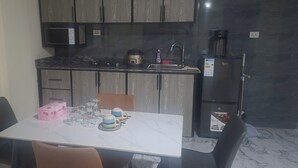 Une cuisine équipée d’une table à manger, de chaises, d’un réfrigérateur et d’un four à micro-ondes.
