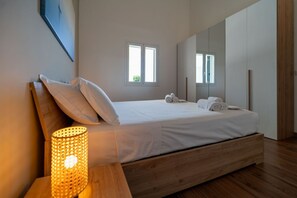 A bedroom with a wooden bed, a bedside lamp, a window, and a mirror. - Villa Oasis - Private garden with jacuzzi by the beach (Siracusa)