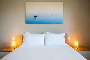 Ein Hotelzimmer mit einem Bett, zwei Nachttischlampen und einem Bild von Segelbooten an der Wand.