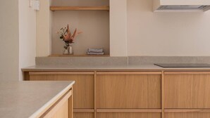 Eine Küche mit Holzausstattung, einer Arbeitsplatte und einem kleinen Regal mit einer Vase und einem gefalteten Handtuch.
