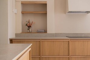 Eine Küche mit Holzausstattung, einer Arbeitsplatte und einem kleinen Regal mit einer Vase und einem gefalteten Handtuch.