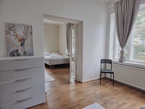 A bedroom with a bed, a chair, a dresser, and a window with curtains. - Historic Central Pyynikki 3BR Apt. Free Parking. (Tampere)