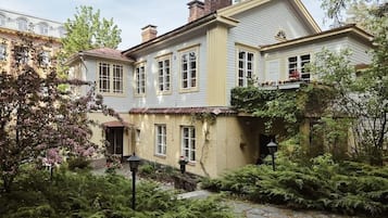 Una casa a due piani con giardino, un camino ben visibile e un piccolo portico.
