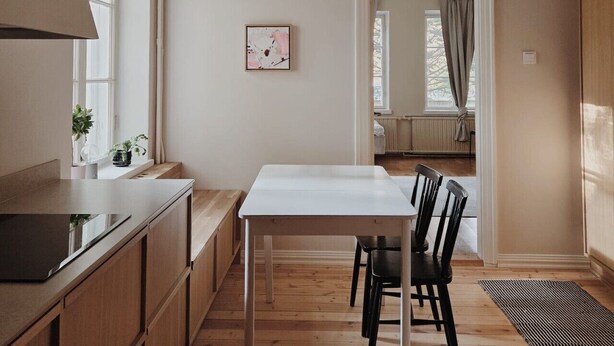 Eine moderne Küche mit Holdekor-Schränken, einer weißen Arbeitsplatte und einem Essbereich mit Tisch und Stühlen.