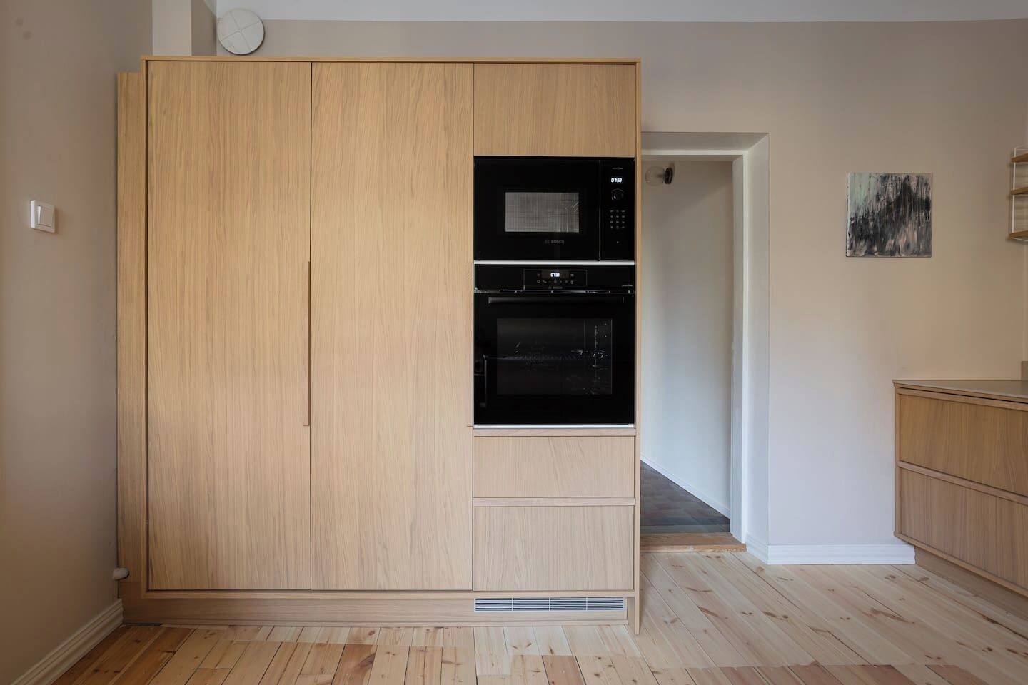 Une chambre dotée d’une armoire en bois, d’un four à micro-ondes encastré et d’un petit four.