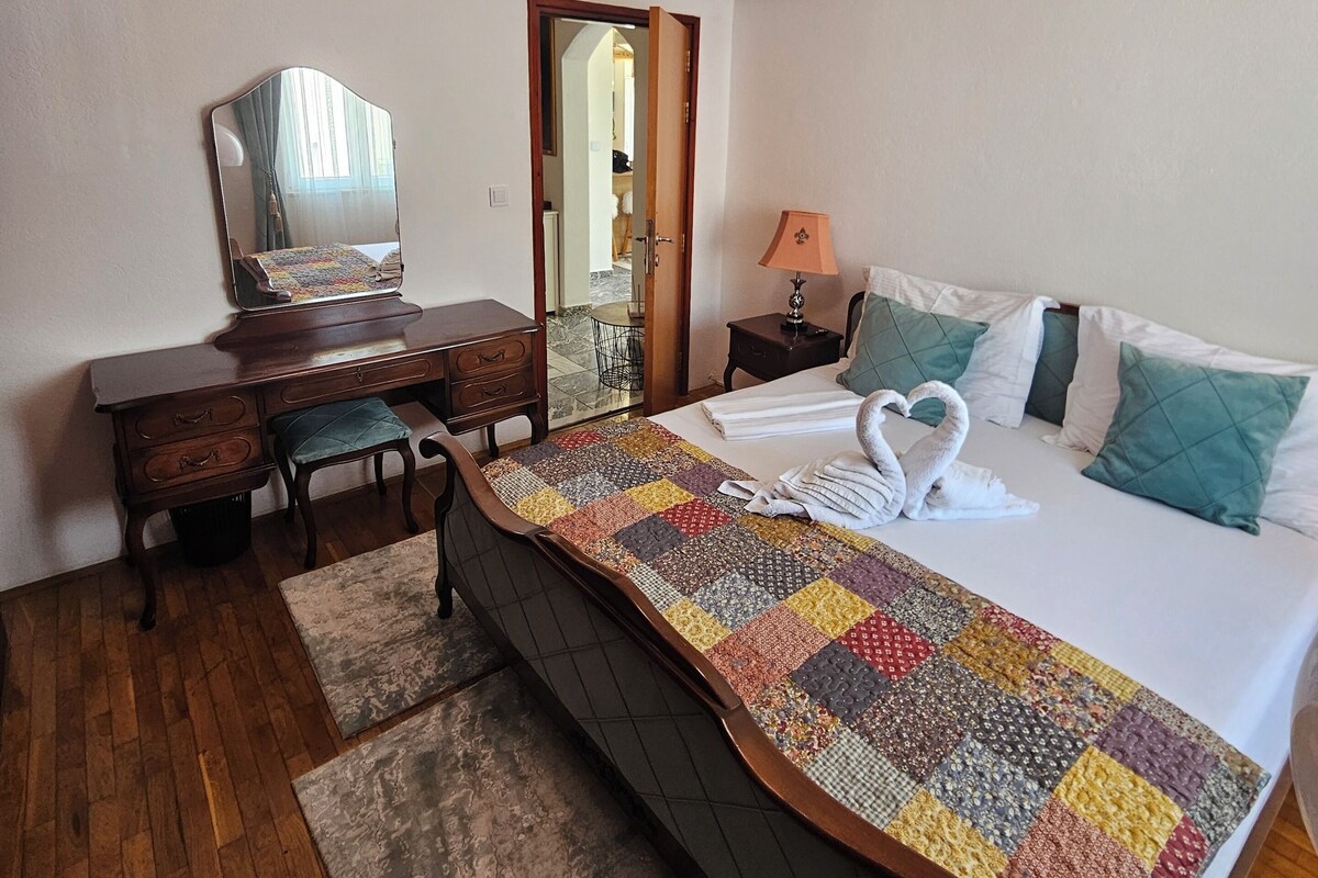 Ein Schlafzimmer mit Bett, Schreibtisch, Stuhl, Spiegel und Lampe.
