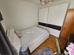 Ett sovrum med en säng, en garderob, en stol och ett litet bord med en lampa.