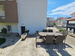 Eine Außenpatio mit Tisch, Stühlen, Topfpflanzen und einem Gebäudeeingang.