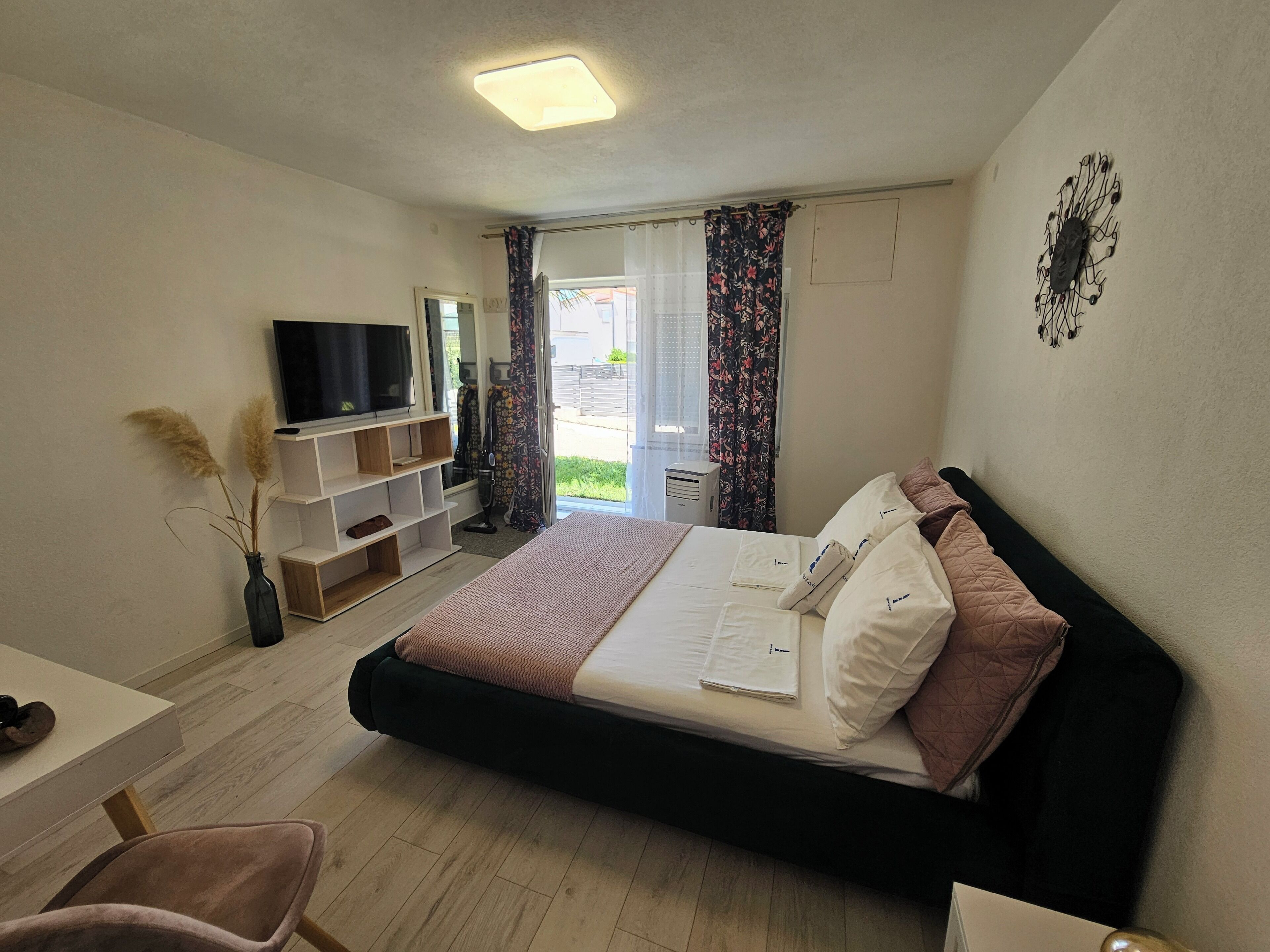 A hotel room with a bed, a TV, a desk, and a chair.